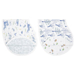 Displayed are two folded aden + anais organic cotton muslin burpy bibs. Both crafted from GOTS-certified 100% organic cotton, they show a white backdrop with blue animals on the left and both flora and fauna with pastel green on the right.