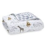 This aden + anais boutique cotton muslin dream blanket features folded, breathable 100% cotton fabric, showcasing elephants, giraffes, and leopards with a reverse blue geometric print. Its extra soft in white with light blue accents.