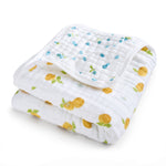 The aden + anais organic cotton muslin dream blanket features a quilted texture with a charming pattern of yellow lemons, green leaves, and small blue dots. Its GOTS certified and perfect for babies.