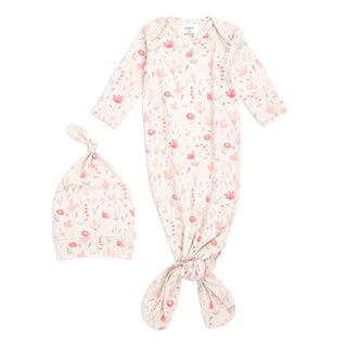 The aden + anais comfort knit™ newborn gown + hat gift set features a cotton-rich floral pattern in pink and blue on white. The gown has long sleeves and a bottom knot, while the matching hat is adorned with a charming top knot.
