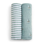 Two organic cotton muslin swaddle blankets by aden + anais are side by side. The left has green and white stripes, while the right shows small sailboat patterns on green. Both soft, textured, and GOTS certified for sustainable baby care.