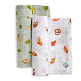 The aden + anais organic cotton muslin swaddle blanket 2 pack includes one light green blanket with carousel, tree, and horse prints, and one white with colorful food illustrations—soft, breathable options for your baby.