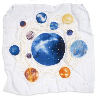 The aden + anais organic cotton muslin swaddle blanket 2 pack includes a white, slightly wrinkled blanket featuring a vibrant solar system print with planets, golden rings, and stars surrounding a large central blue planet.