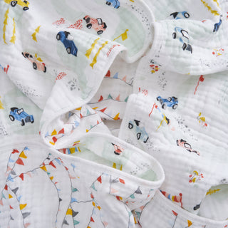 The aden + anais essentials cotton muslin dream blanket features a playful transportation-themed print with colorful cars, roads, cones, and flags. Soft and lightweight, it's perfect for newborns looking for comfort and whimsy.