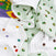 A close-up of the aden + anais essentials cotton muslin dream blanket, crumpled and cozy, shows colorful polka dots and Very Hungry Caterpillar illustrations on a light green background.