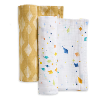 The aden + anais essentials cotton muslin swaddle blanket 2 pack includes a yellow geometric diamond design and a white blanket with colorful scattered diamonds; both are soft, breathable cotton muslin and neatly folded together.