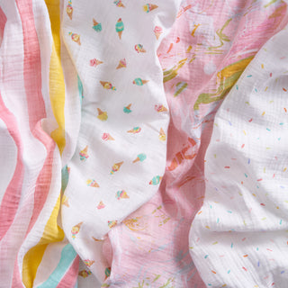 The aden + anais essentials cotton muslin swaddle blanket 4 pack features soft, lightweight blankets in pastel prints like ice cream cones, stripes, and sprinkles in pink, yellow, teal, and white.