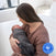 A woman sits on a bed, gently cradling a sleeping baby wrapped in a HALO SuperSoft Bamboo Swaddle TOG 2.0. The image displays a Best of BabyCenter Award Winner 2025 badge in the lower right corner.