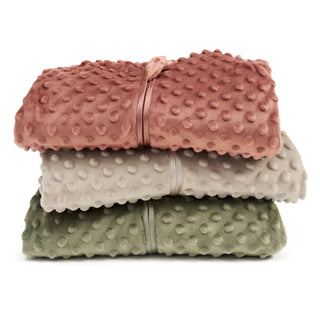 Three folded HALO Swaddle Plushy Dot Velboa TOG 3.0 blankets in pink, beige, and green are stacked together, each featuring a raised dot pattern and tied with a matching ribbon for a cozy, stylish look.