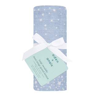A rolled-up blue aden + anais boutique 100% cotton muslin swaddle blanket with a white star pattern is tied with a white ribbon. It has a green tag highlighting its breathable and absorbent qualities.
