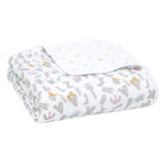 The essentials cotton muslin dream blanket by aden + anais is a folded white baby blanket featuring gray letters and colorful cartoon animals like giraffes, elephants, and rabbits. Lightweight and soft, its underside has a subtle pattern with smaller animals.
