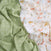 The aden + anais essentials cotton muslin swaddle blanket 2 pack includes crumpled, breathable, and gentle fabrics: a green swatch with arrow patterns and a white one featuring foxes and trees.