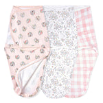 The aden + anais Disney™ essentials easy swaddle wrap quick change 3 pack (TOG 1.0) is shown in soft, pastel prints—pink floral, white animal/floral sketches, and pink gingham plaid—with an escape-proof fit for safer sleep.