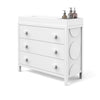 The Child Craft F01792 Universal Changing Table Topper in matte white features three drawers, large round knobs, and circular side accents. On top are two dispensers and a changing pad for convenient diaper changes.