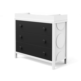 A modern Child Craft dresser with three black drawers and round knobs, a white frame, bold circular side accents, and compatible with the F01792 - Universal Changing Table Topper in Lunar Gray for added functionality.