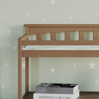 The Child Craft Flat Top Baby Changing Table in Dusty Heather sits against a light green wall with white stars. Two books are stacked on its lower shelf, making it ideal for nursery storage and organization.
