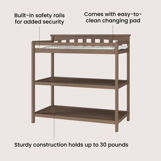 The Child Craft Flat Top Baby Changing Table in Dusty Heather features built-in safety rails, a baby changing pad, two open shelves for storage, and supports up to 30 lbs.