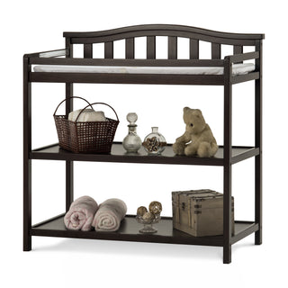 The Child Craft Arch Top Baby Changing Table in Jamocha is classic nursery furniture with a curved back, padded changing pad, and two shelves for towels, glass bottles, a teddy bear, decorative balls, and a wooden box.