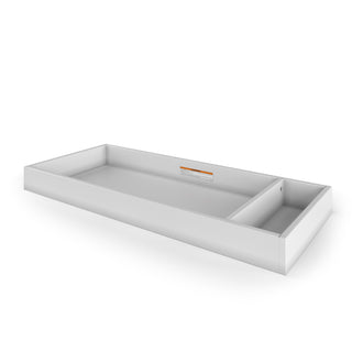 The Child Craft Legacy Changing Table Topper in matte white is a rectangular metal dresser tray with raised edges and a small divided compartment. Shown against a plain white background, it features a label with text near the back edge inside the tray.