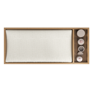 Top view of the Child Craft Legacy Changing Table Topper in Biscotti, featuring a large rectangular cream cushion and a side section with four neutral-toned ceramic cups and bowls.