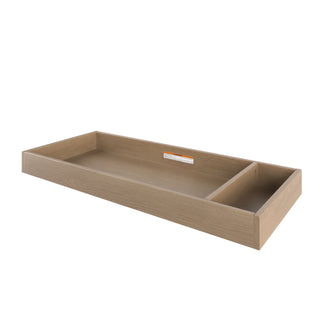 The Child Craft F01792 Universal Changing Table Topper in Nutmeg features one large and one small compartment, and can be used as an under-bed storage drawer or repurposed as a dresser changing kit or baby changing tray for versatility.