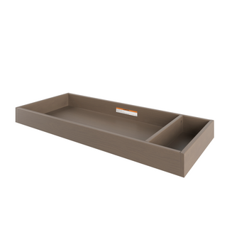 The Child Craft F01792 Universal Changing Table Topper in Dusty Heather is a rectangular wooden tray with a divider creating large and small compartments. The back features a small sticker with text.