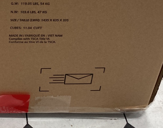 Close-up of a cardboard box for the Child Craft Atwood 4-in-1 Convertible Crib, Lunar Gray, showing shipping info, dimensions, weight, and an envelope icon with motion lines. Red tape is visible at the bottom of the box.