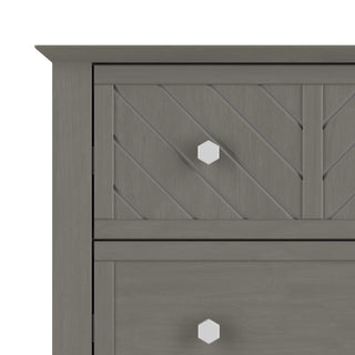 A close-up of the Child Craft Atwood 4-Drawer Chest in Lunar Gray highlights the corner, two drawers with geometric white knobs, and diagonal grooves on the top drawer.