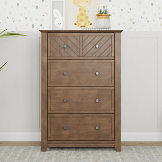 The Child Craft Atwood 4-Drawer Chest in Cocoa Bean features a chevron-patterned top drawer. It's shown on a gray rug with potted plants on top and a nursery-themed wall in the background.