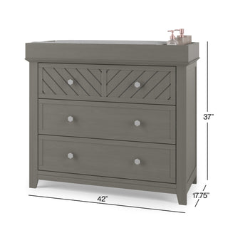 A Child Craft F01792 Universal Changing Table Topper in Lunar Gray sits atop a dresser with 2 small, geometric-patterned top drawers, 2 large lower drawers, and silver knobs. Dimensions: 42"W x 17.75"D x 37"H. Bottles rest on the topper.