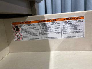 The Atwood 3-Drawer Dresser by Child Craft, in Lunar Gray, features a warning label in English, French, and Spanish with caution symbols for tipping hazard, child climbing, and TV placement to help prevent tip-over accidents.