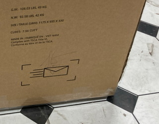 A close-up of a Child Craft Atwood 3-Drawer Dresser box on a tiled floor shows weight, dimensions, an envelope graphic with motion lines, and text saying it’s made in Vietnam and TSCA compliant. The dresser color is Lunar Gray.