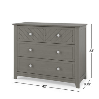 The Child Craft Atwood 3-Drawer Dresser in Lunar Gray features a geometric-patterned top drawer, silver knobs, and angled corner legs. Measures 33"H x 42"W x 17.75"D.