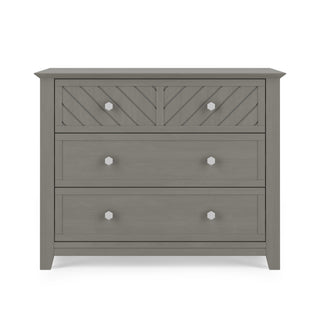 The Child Craft Atwood 3-Drawer Dresser in Lunar Gray features silver hexagonal knobs, a chevron-patterned top drawer, and two smooth lower drawers.