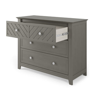 The Child Craft Atwood 3-Drawer Dresser in Lunar Gray features a modern, clean-lined design with simple geometric drawer fronts, round metal knobs, and a partially open top drawer.