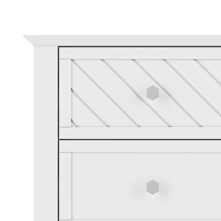The Child Craft Atwood 3-Drawer Dresser in Matte White features geometric handles, a top drawer with diagonal grooves, and a smooth lower drawer. Only the upper left corner of the dresser is shown.