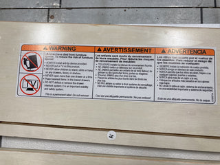 The Atwood 3-Drawer Dresser by Child Craft includes a warning label to anchor the unit and prevent tip-over. Features safety icons, bold headings, and a crossed-out child climbing image in English, French, and Spanish. Cocoa Bean finish.