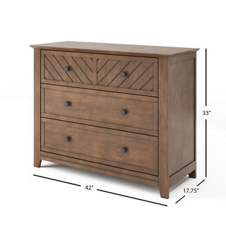 The Child Craft Atwood 3-Drawer Dresser in Cocoa Bean features a chevron-patterned top drawer, black round knobs, and measures 42"W x 33"H x 17.75"D.