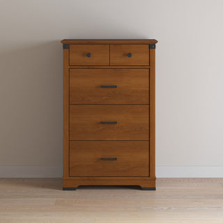 The Child Craft Redmond 3 Piece Nursery Set includes a wooden chest with four drawers, black metal handles, and stands on a wooden floor against a plain light wall—perfect for nursery furniture.