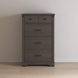 The Child Craft Redmond 4 Drawer Chest in Dapper Gray stands against a plain light-colored wall on a wooden floor, featuring two small top drawers and two larger drawers below.