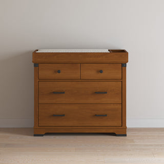 The Child Craft Redmond 3 Drawer Dresser in Coach Cherry features a spacious design that can be paired with a changing table topper for added functionality.