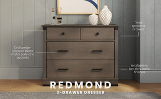 The Child Craft Redmond 3 Drawer Dresser in Dapper Gray has black metal pulls and craftsman-inspired style, making it perfect for a nursery. Two vases and a photo frame on top add a decorative touch.