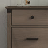 A close-up of the Child Craft Redmond 3 Drawer Dresser in Dapper Gray shows distinctive black hardware, with glass containers partially visible on top of this stylish nursery dresser.