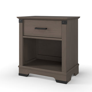 The Child Craft Redmond Nightstand in Dapper Gray features a single drawer, open lower shelf, and black metal accents on the corners and handle, shown against a white background.
