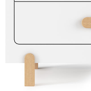 A close-up of the Child Craft Park Heights 4-Drawer Chest in matte white, featuring simple black outlines, a wooden handle, and light Brazilian hardwood legs, set against a plain background.