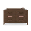 The Child Craft Kieran 6-Drawer Double Dresser in Toasted Chestnut features six drawers with pink handles, topped with a changing pad and pink containers on the right. The background is plain white.
