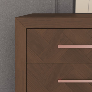 Close-up of the Child Craft Kieran 6-Drawer Double Dresser in Toasted Chestnut, showcasing its herringbone pattern and sleek metallic handles, set against a gray textured wall.