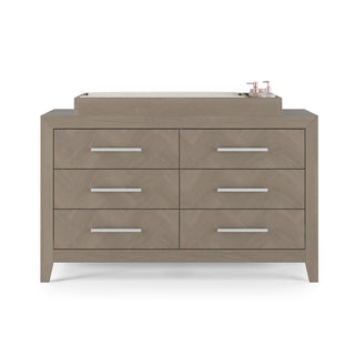 The Child Craft Kieran 6-Drawer Double Dresser in Crescent Gray features silver handles, a cushioned changing pad on top, and two small containers in the upper right corner.