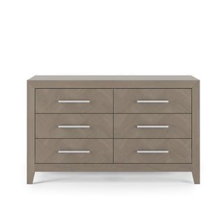 The Child Craft Kieran 6-Drawer Double Dresser in Crescent Gray features a modern geometric design, angled legs, six spacious drawers, and sleek silver handles, shown against a white background.