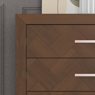A close-up of the Child Craft Kieran 5-Drawer Chest in Toasted Chestnut showcases its herringbone pattern, two drawers with modern metal handles, and a background including a wall, framed art, and a white vase.